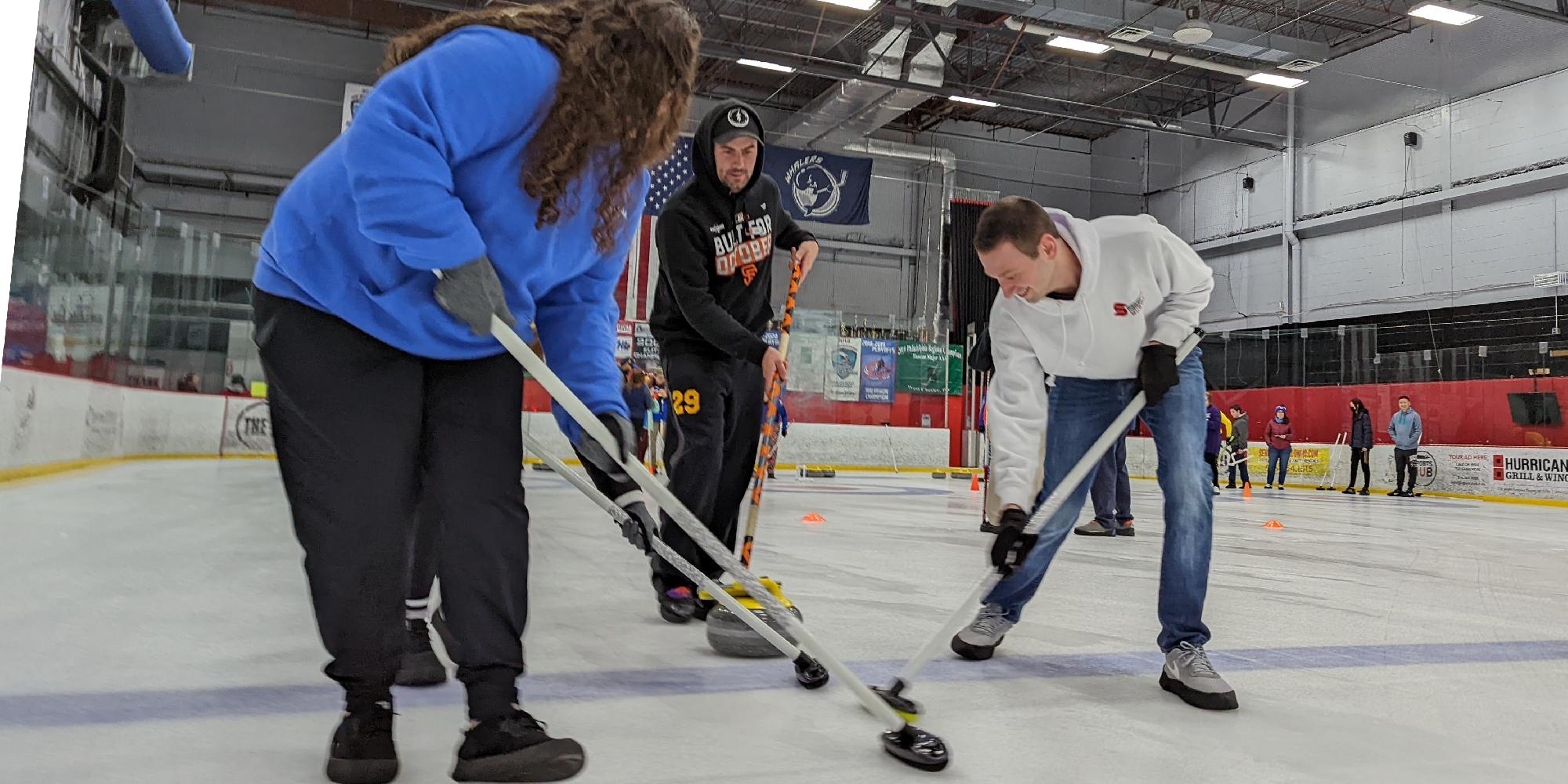 People learning to sweep a curling stone on the ice